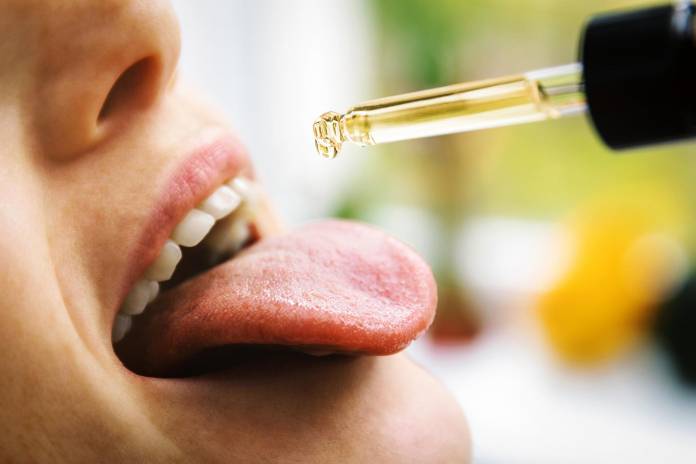 CBD Öl auf die Zunge träufeln